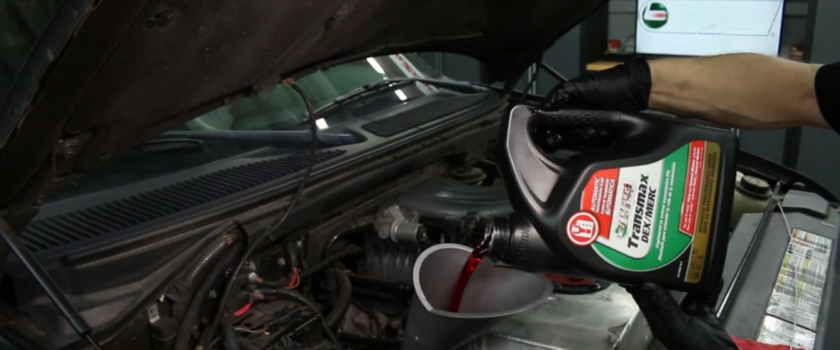 signs of transmission problems. Mechanic pouring fresh transmission fluid into a vehicle's engine during routine maintenance.