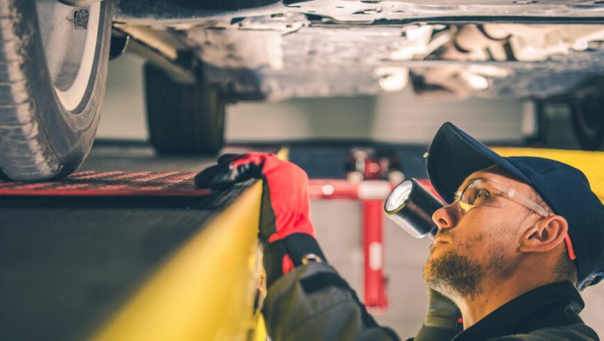 Warning Signs Of Transmission Problems. rofessional mechanic inspecting under a vehicle for transmission problems at a repair shop.