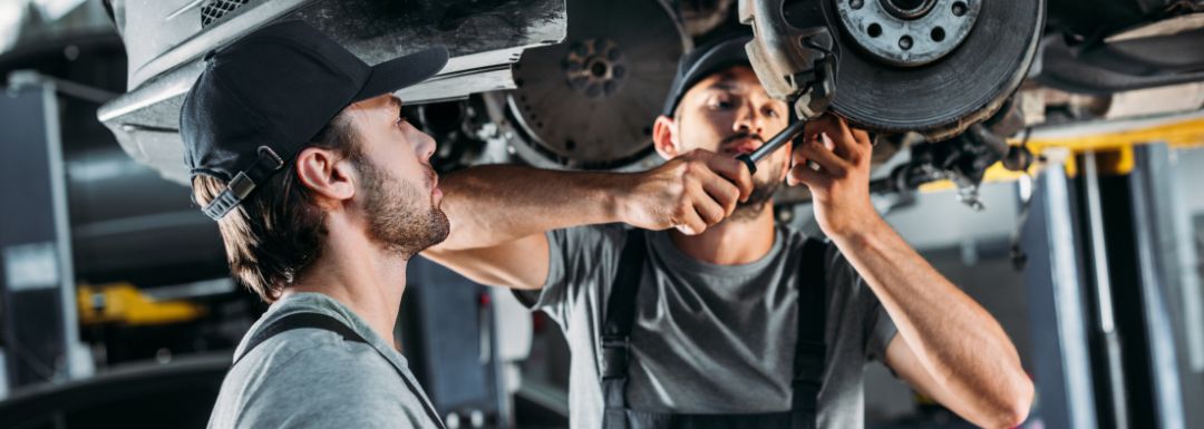 Mechanic performing engine maintenance under car hood at hudsonville auto repair