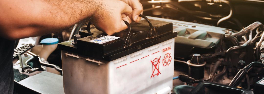 Mechanic's hands installing car battery at hudsonville auto repair