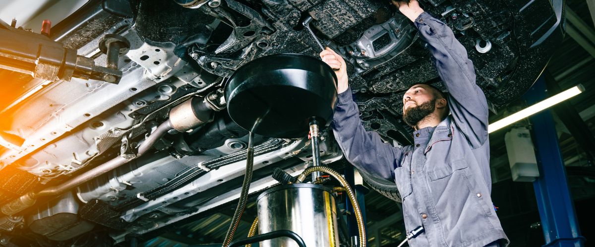 Mechanic performing lube, oil, and filter service underneath a raised vehicle in Grand Rapids